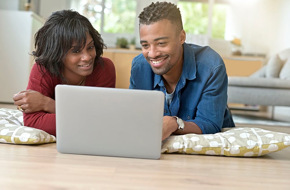 Jeune couple recherchant le meilleur système de surveillance du glucose en continu sur un ordinateur portable.