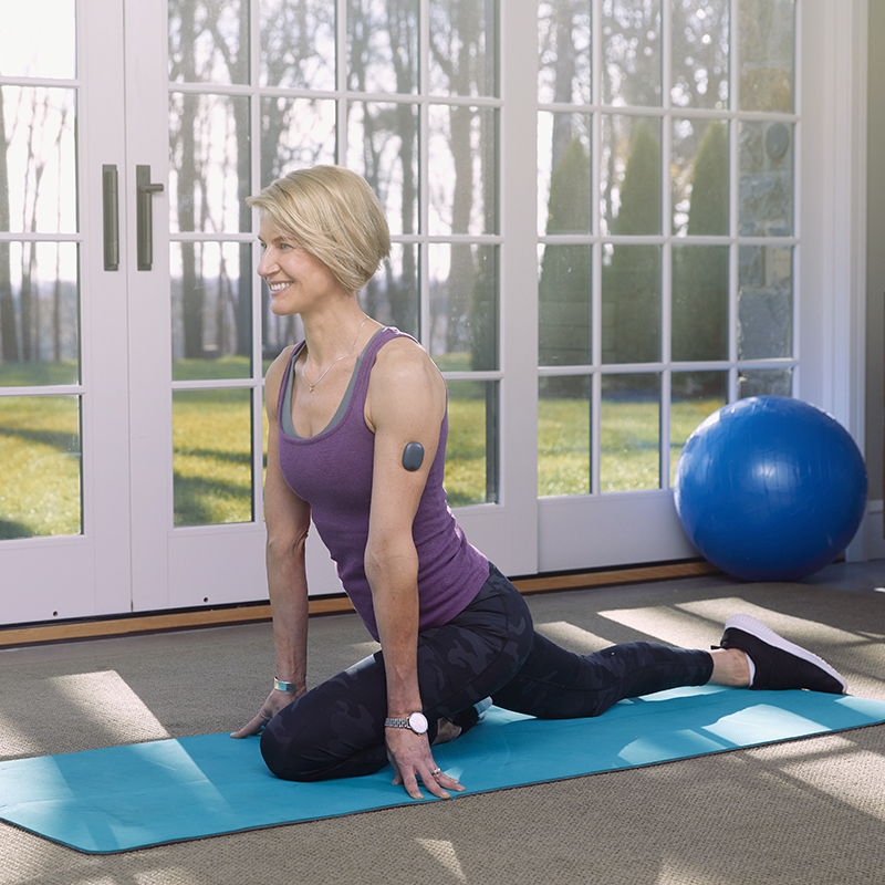 Donna in una posizione di yoga mentre indossa un CGM Eversense.