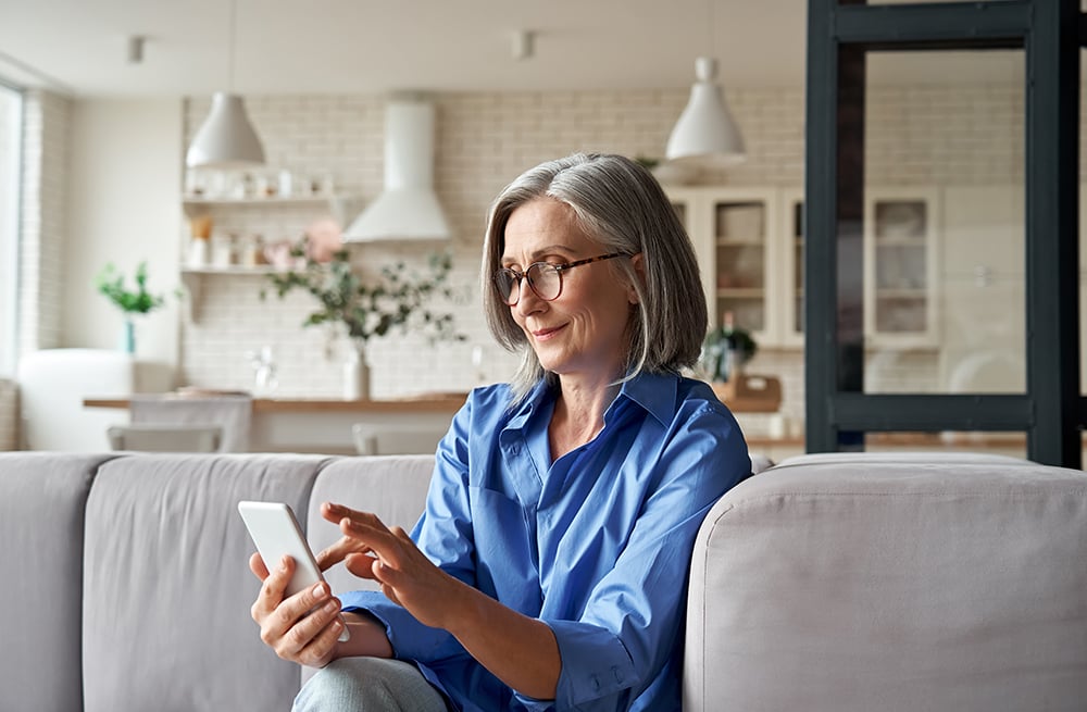 Frau schlägt auf Handy Informationen zu Kosten des Eversense E3 System CGM nach