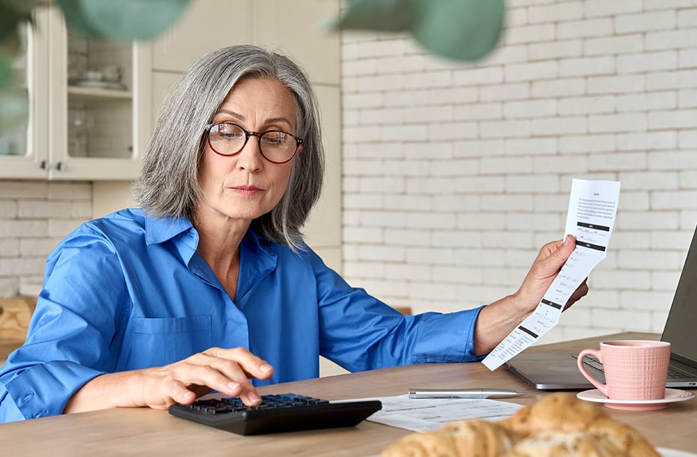 Une femme utilisant une calculatrice pour déterminer le prix d’un CGM sans assurance.