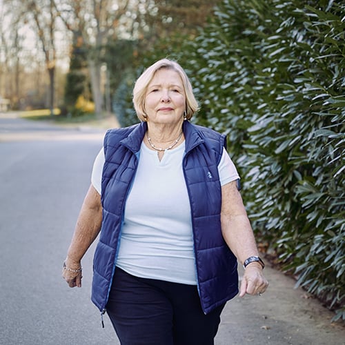 Une femme se baladant et portant un CGM Eversense doté d’un capteur de glucose.